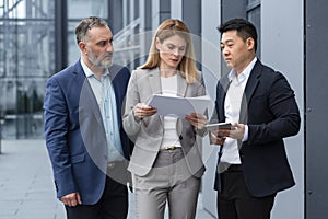 Diverse business team three colleagues employees discuss documents contract outside office building businessman and