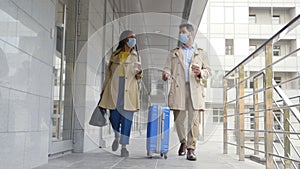 Diverse businessman and businesswoman in safety mask with luggage traveling on business trip