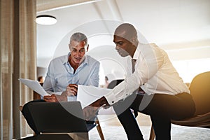 Diverse businessmen discussing work on a laptop in an office