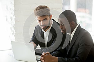 Diverse businessmen in suits analyzing online project together o