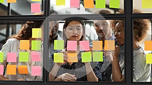 Diverse businesspeople discussing, planning project on sticky papers together photo