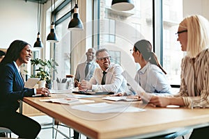 Diverse businesspeople laughing during a meeting around an offic