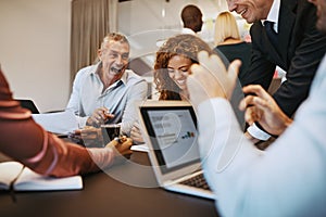 Diverse businesspeople laughing while meeting together in an off