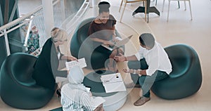 Diverse businesspeople in a meeting, planning and discussing paperwork together as a team in a modern office. Top view