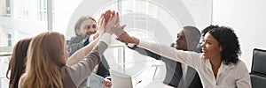 Diverse businesspeople sitting at desk celebrating success giving high five