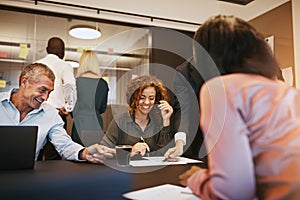 Diverse businesspeople smiling while meeting together in an offi