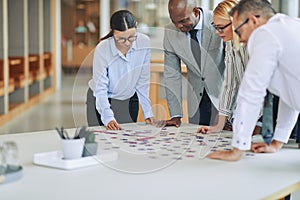 Diverse businesspeople solving a jigsaw puzzle together in an of