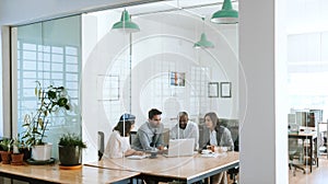 Diverse businesspeople using a laptop together in an office boardroom