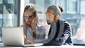 Diverse businesspeople work on laptop discuss project together