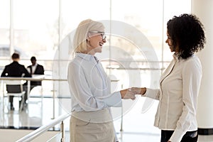 Diverse businesswomen shaking hands greeting each other