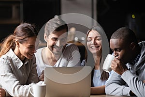 Diverse cheerful friends sitting in cafe watching video on computer