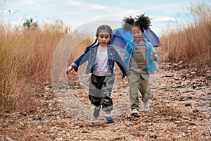 Diverse children of asian and african american girl having fun walking and playing together in natural park