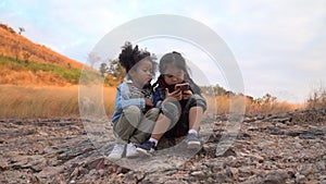 diverse children friend african american and asian girl using smartphone together in nature on mountain with sunlight . group of