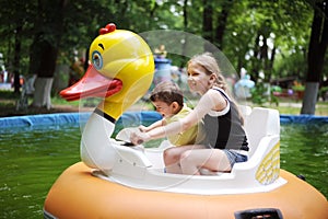 Diverse children - a little boy and a teenage girl riding on a water attraction