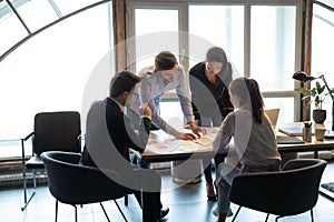 Diverse colleagues brainstorm discuss company paperwork at meeting