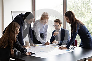 Diverse colleagues brainstorm discuss paperwork at meeting