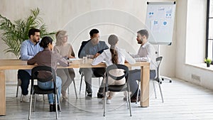 Diverse colleagues discuss business ideas at meeting in office