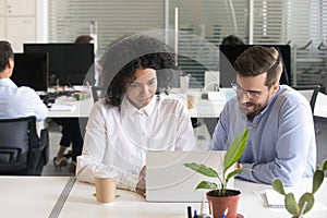 Diverse colleagues discussing computer work at workplace photo