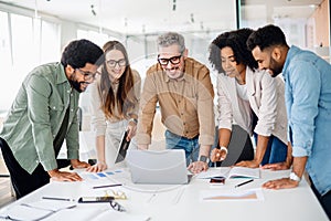 Diverse colleagues gather around a laptop with bright expressions photo