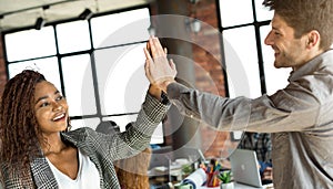 Diverse colleagues giving high five at office meeting