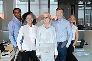 Diverse colleagues led by company chief posing for camera