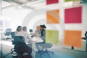 Diverse colleagues meeting together inside of a glass walled off