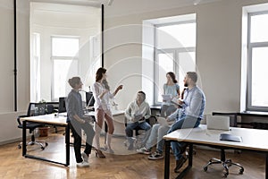 Diverse colleagues office employees speaking during informal briefing in coworking