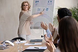 Excited businesspeople applaud thanking middle-aged businesswoman presenting photo