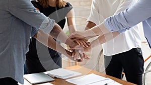 Diverse colleagues stack hands engaged in teambuilding activity