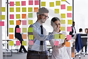 Diverse colleagues write on attached sticky notes working in office