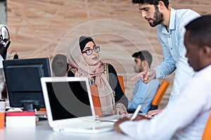 Diverse college students using laptop and talking, learning exchanging ideas