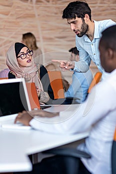 Diverse college students using laptop and talking, learning exchanging ideas