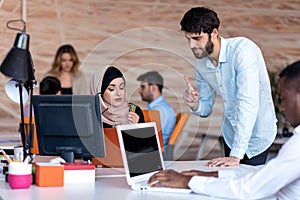 Diverse college students using laptop and talking, learning exchanging ideas photo