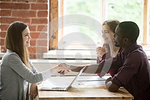 Diverse couple handshaking realtor buying new home, mortgage inv