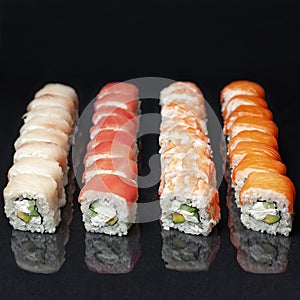 Diverse delicious sushi roll set on a black background with reflection, menu