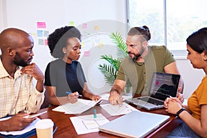 Diverse development team discusses code during code review meeting, programming