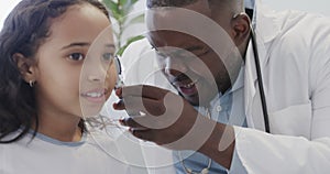 Diverse doctor examining sick girl patient with otoscopy in hospital in slow motion