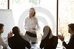 Diverse employees applaud greeting female speaker at meeting