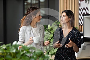 Diverse employees chatting during coffee break in modern office