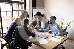 Diverse employees discuss business paperwork at meeting