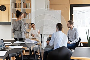 Diverse employees discuss project on flip chart