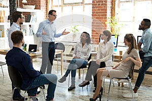 Diverse employees listening to male manager speaking at group meeting