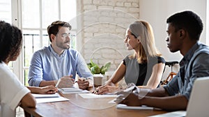 Diverse employees listening to team leader at briefing