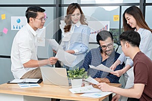 Diverse employees in office brainstorming while discussing ideas for new project, using laptop. Multiracial coworkers gather in