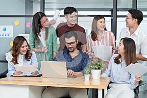 Diverse employees in office having fun during brainstorming while discussing ideas for new project, using laptop. Multiracial