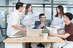 Diverse employees in office having fun during brainstorming while discussing ideas for new project, using laptop. Multiracial