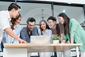 Diverse employees in office having fun during brainstorming while discussing ideas for new project, using laptop. Multiracial