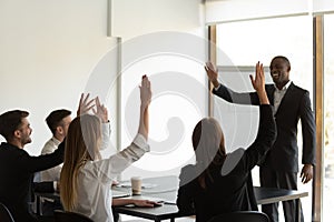 Diverse employees raise hands interacting with male coach
