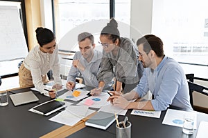 Diverse employees team coworkers discussing project strategy, working with documents