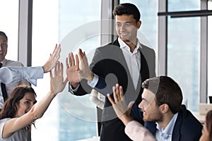 Diverse employees team giving high five at meeting, celebrating success